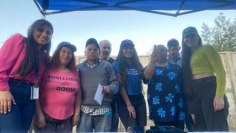 Un grupo de personas posando juntas bajo un toldo en un ambiente al aire libre.