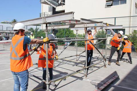 Un grupo de trabajadores colabora en la instalación de un andamio en una obra.