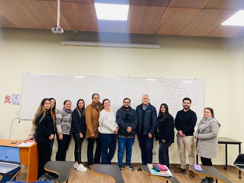 Grupo de personas posando frente a una pizarra en un aula.