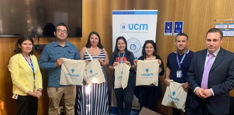 Grupo de personas sosteniendo bolsas con el logo de UCM en un evento.