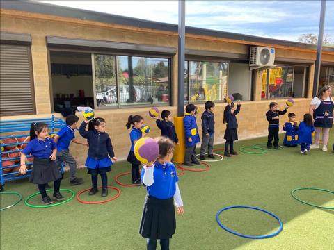 Un grupo de niños en un patio de escuela jugando con aros y pelotas.