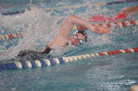 Un nadador compitiendo en una piscina durante una carrera de estilo libre.