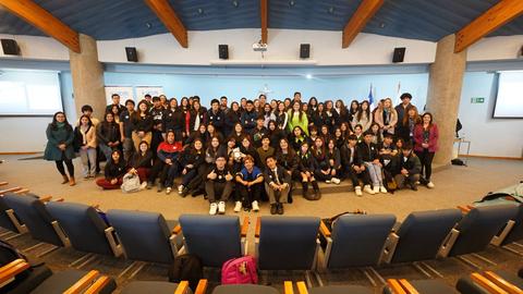Grupo numeroso de personas posando juntas en un auditorio.