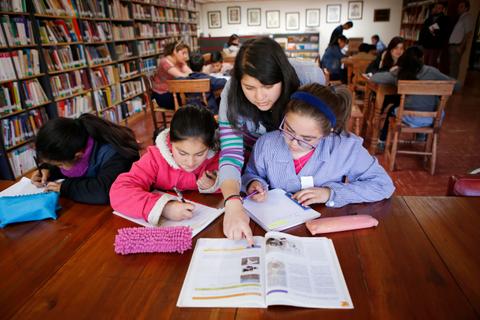 Un grupo de niños estudia y trabaja en una biblioteca.