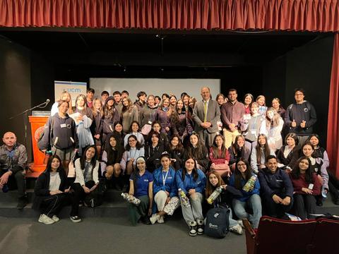 Un grupo grande de personas se reúne en un escenario para una foto grupal en un evento.