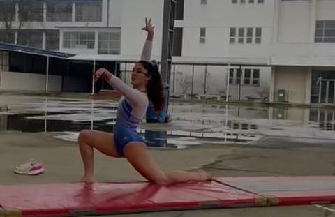 Una gimnasta realiza una rutina de ejercicios sobre una colchoneta en un entorno escolar.