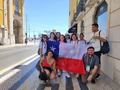 Grupo de personas sosteniendo una bandera chilena en una calle soleada.