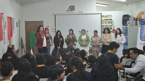 Un grupo de mujeres se presenta ante un público de niños en un aula escolar.