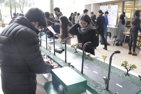 Un grupo de estudiantes trabaja en un proyecto educativo sobre una maqueta de una calle con detalles urbanos.