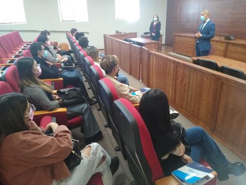 Un grupo de personas escucha una charla en una sala de audiencias.