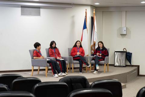 Cuatro jóvenes se sientan en un escenario durante una charla o presentación.