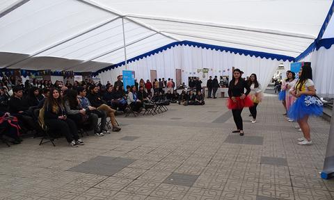 Un grupo de chicas baila en un evento escolar mientras una gran multitud observa.
