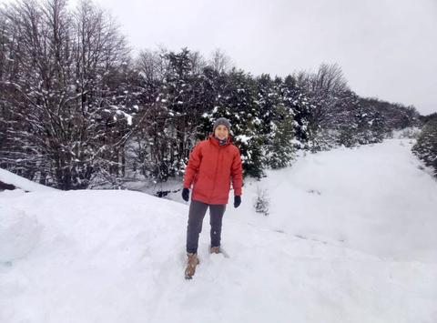 Una persona está de pie en la nieve, rodeada de árboles cubiertos de nieve.