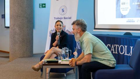 En la imagen se observa a dos personas durante una charla en un evento relacionado con el trabajo social.