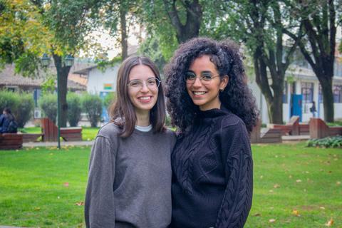 Dos jóvenes sonriendo en un parque al aire libre.