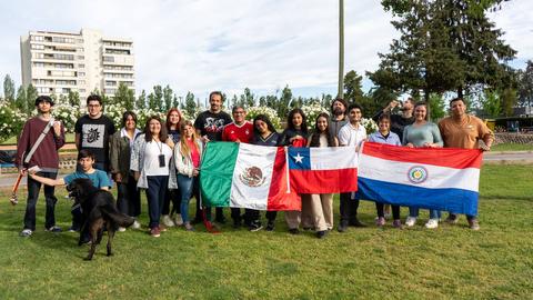 Un grupo de personas de diversas nacionalidades sosteniendo banderas en un parque.