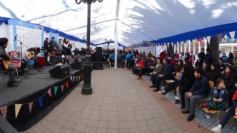 Un evento al aire libre con un escenario donde una banda está tocando música frente a una gran audiencia.