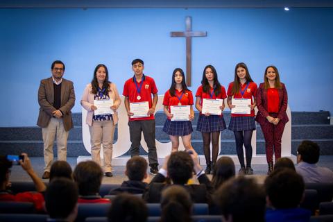 Un grupo de estudiantes recibe premios en un evento con un fondo de iglesia.