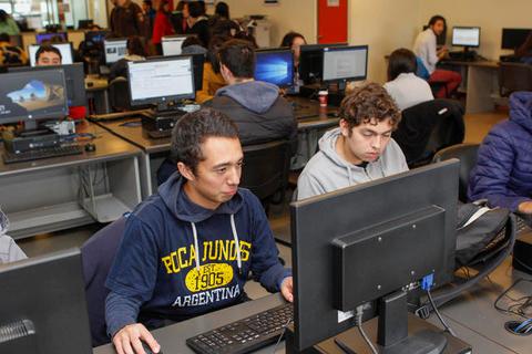Un grupo de estudiantes trabaja en computadoras en un aula.