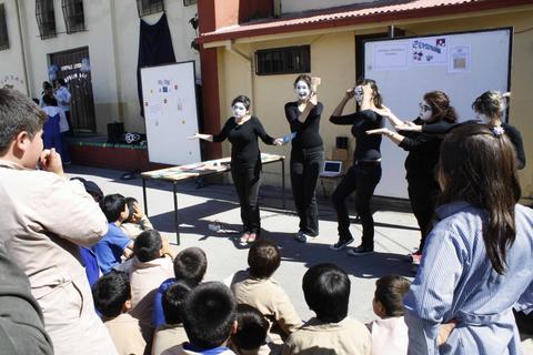 Un grupo de personas actúa frente a un público infantil en un ambiente escolar.