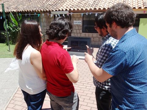 Un grupo de cuatro personas observa algo en un dispositivo en un ambiente al aire libre.