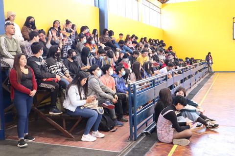 Un grupo numeroso de personas sentadas en gradas en un lugar cerrado.