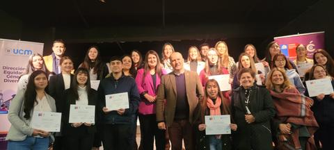 Un grupo de personas sonrientes sosteniendo certificados en un evento de reconocimiento.