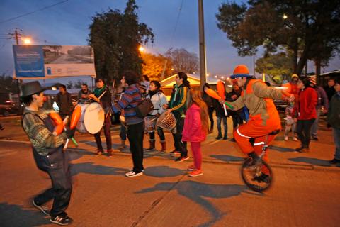 Una celebración en la calle con personas bailando y un malabarista en un monociclo.
