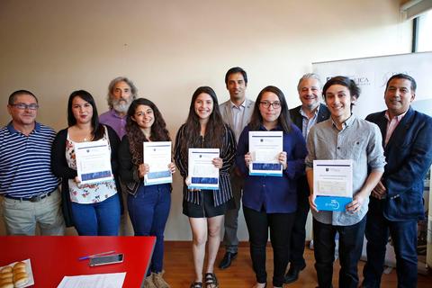 Un grupo de personas sonrientes sostiene certificados en un ambiente de celebración.