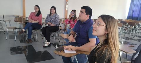 Un grupo de personas sentadas en un aula, escuchando atentamente.
