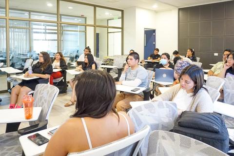 Un grupo de estudiantes sentados en un aula, prestando atención a una presentación.