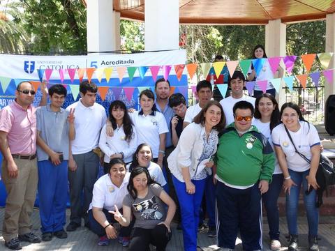 Grupo de personas posando sonrientes en un evento al aire libre frente a una pancarta de la universidad.