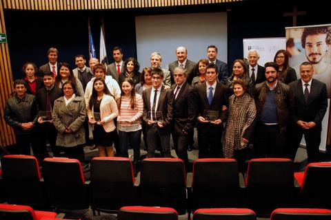 Un grupo de personas posan juntas en un evento de premiación en un auditorio.