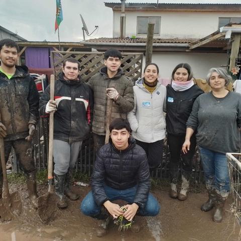 Grupo de personas en un entorno rural, vestidas con ropa de trabajo y con herramientas de jardinería.