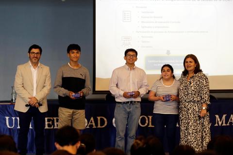 Cuatro personas en un evento académico sosteniendo premios o reconocimientos.
