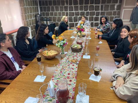 Un grupo de mujeres se reúne alrededor de una mesa decorada con flores y alimentos.