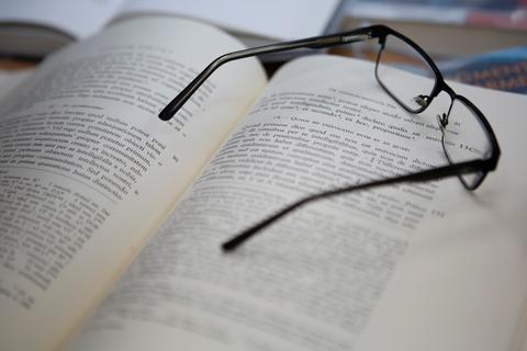 Unas gafas negras descansan sobre un libro abierto con texto impreso.