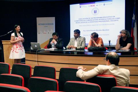 Una presentadora está exponiendo en una conferencia educativa mientras un panel de expertos la escucha.