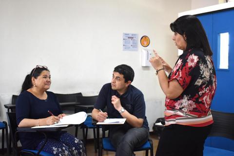Tres personas participan en una conversación en un aula.