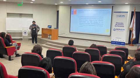 Una presentación sobre temas de salud pública en una sala con asistentes sentados.