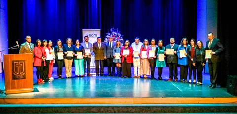 Un grupo de personas posando en un escenario tras recibir certificados en un evento formal.