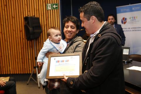 Una familia celebra la entrega de un reconocimiento mientras sostienen a un bebé.