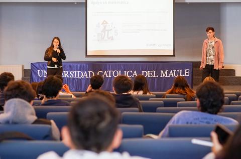 Un grupo de estudiantes escucha a dos presentadoras en una conferencia sobre matemáticas.