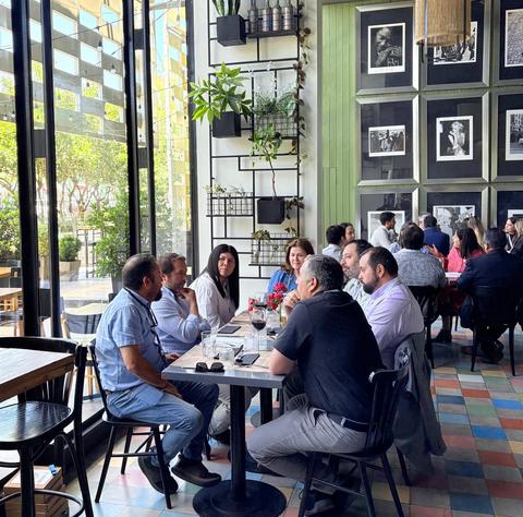 Un grupo de personas sentadas alrededor de una mesa en un restaurante, conversando y disfrutando del ambiente.