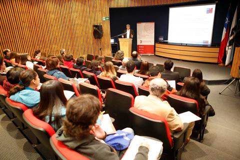 Una conferencia en un auditorio con un orador frente a un público atento.