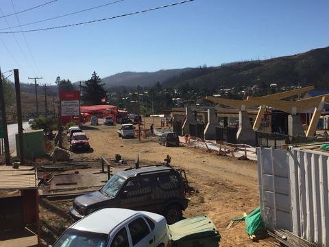 La imagen muestra una zona de construcción con varios vehículos y un paisaje rural de fondo.