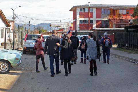 Un grupo de personas camina por una calle de un barrio urbano.
