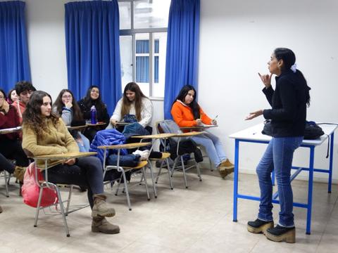 Una profesora está presentando un tema a un grupo de estudiantes en un aula.