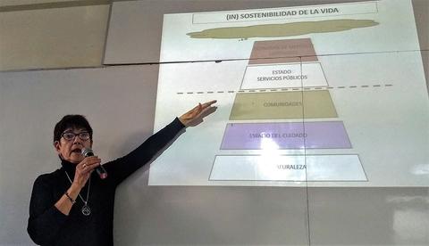 Una mujer explica un gráfico sobre la sostenibilidad de la vida, señalando con una mano hacia la presentación.