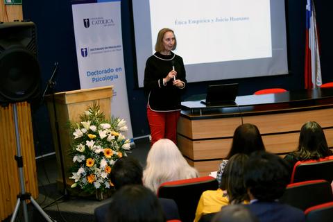 Una presentadora habla frente a una audiencia en un evento académico en Chile.